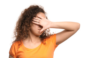 Young African-American woman covering her eyes on white background