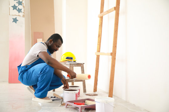 Male African-American decorator doing repair in room