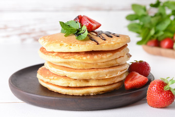 Tasty pancakes with strawberry on table