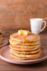 Tasty pancakes with butter on wooden table