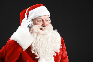 Portrait of Santa Claus listening to music on dark background