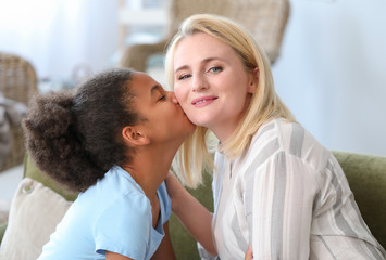 Little African-American girl kissing her mother at home