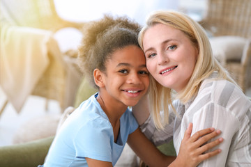 Happy woman with her African-American daughter at home