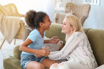 Happy woman with her African-American daughter at home