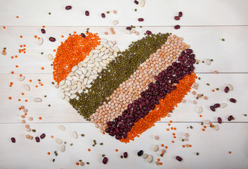beans, lentils and beans laid out in the form of a heart on a white wooden background, top view. The concept is healthy eating.