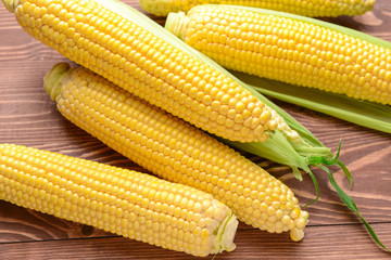 Fresh corn cobs on wooden background