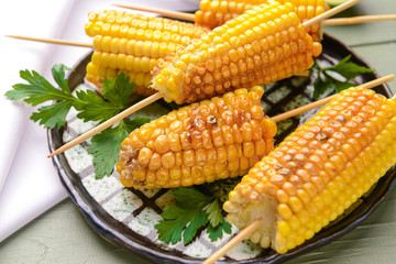 Plate with tasty grilled corn cobs on table