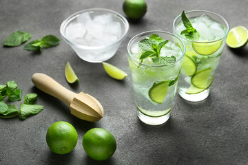 Glasses of fresh mojito, lime and juicer on table