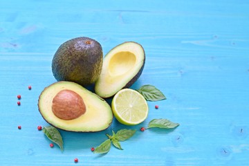 Concept of healthy food. Top table with fresh cut avocado and half lime on blue wooden background. Copy text.