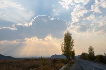 the road leading to the temple on top of the mountain in the rays of the setting sun with a huge cloud in the sky.