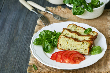 Casserole with zucchini, cheese and fresh herbs on a white plate