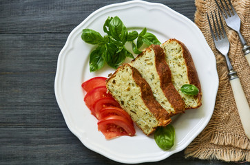 Casserole with zucchini, cheese and fresh herbs on a white plate