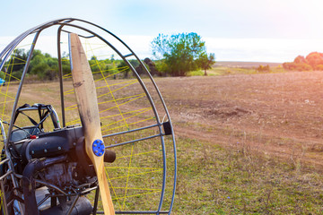 Closeup of a propeller with a motor-paraglider motor against the background of a field.