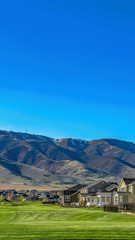 Obraz premium Vertical frame Charming homes and towering mountain under clear blue on a sunny day