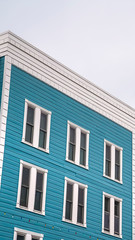 Vertical Residential building with blue exterior wall and vertical sliding windows