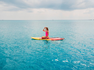 Aerial view of woman on stand up paddle board in ocean.