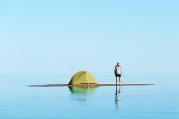 A man on the island with a tent. Man in focus, background blurred