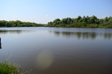 Summer landscape with lake in the field and blue sky.