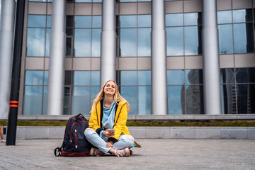 Beautiful girl uses smartphone and sits on skateboard.