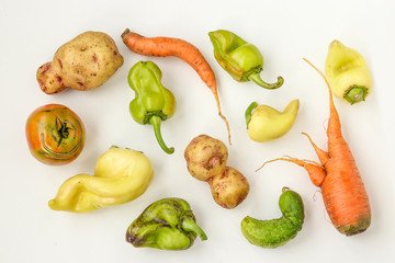 Ugly vegetables: potatoes, carrots, cucumber, peppers and tomatoes on white background, ugly food concept, horizontal photo, top view