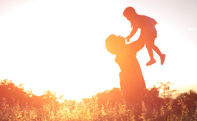 silhouettes of father and little baby playing at sunset