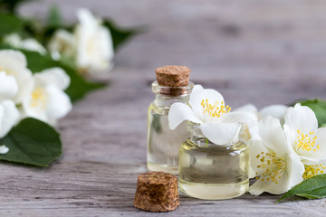 Fototapeta na wymiar Essential jasmine oil. Massage oil with jasmine flowers on a wooden background