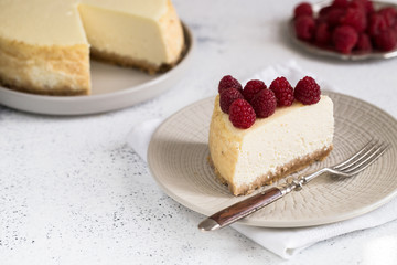 Slice Of Classical New York Cheesecake with raspberries On White Plate. Closeup View. Home bakery concept
