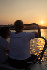 Fototapeta premium mom and daughter watching the sunset sitting on the ship