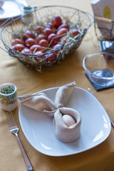 Real family table set for Easter breakfast in traditional Polish home. Basket filled with eggs colored with onion skins.