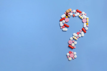 Question mark made of lots of pills and capsules on color background. 