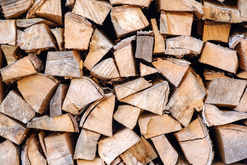Background of chopped, sawn and stabbed stacked wooden logs.