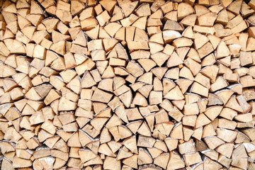 Background of chopped, sawn and stabbed stacked wooden logs.