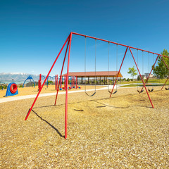 Fototapeta premium Square frame Swings on a park with playground pavilion lake and mountain in the background