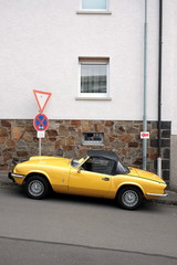 Gelber britischer Roadster und Sportwagen Klassiker mit schwarzem Verdeck der Siebzigerjahre im...