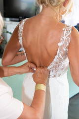Bride getting dressed by her mother bridesmaid in wedding day
