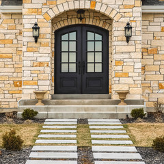 Square frame Home facade with stone brick wall double glass paned door and arched windows