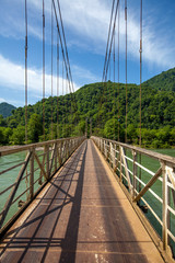 Old metal bridge over river in mountains valley