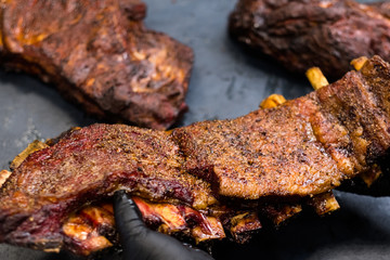 Grill restaurant kitchen. Closeup of smoked seasoned pork ribs in professional chef hands.