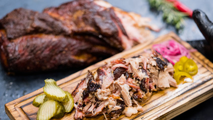 Grill restaurant menu. Closeup of smoked pulled pork with pickles on rustic wooden board.