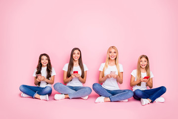 Nice attractive lovely cheerful girlish girls sitting on floor crossed legs chatting using app 5g connection browsing web internet online leisure free time isolated over pink pastel background