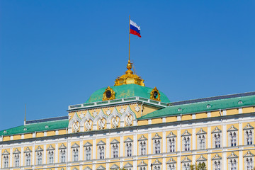 Obraz premium Wielki Kreml Palace z macha flagą Federacji Rosyjskiej na dachu na tle błękitnego nieba w słoneczny poranek