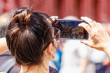 Fototapeta premium Woman takes a photo on the modern smartphone on Red Square in Moscow at sunny summer day closeup