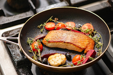 Tasty salmon steak in pan with ingredients.