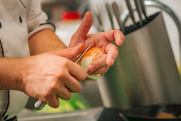Professional chef peeling onion, close-up.