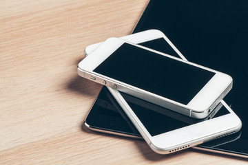 Digital tablet and mobile phone. Electronic devices on wooden table, close up.
