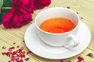 Cup of green tea on table with fresh peony flowers