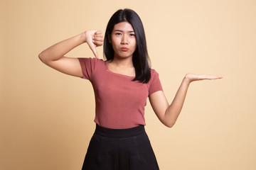 Young Asian woman show palm hand and thumbs down.