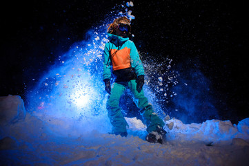 Active female snowboarder dressed in a orange and blue sportswear standing on the snow