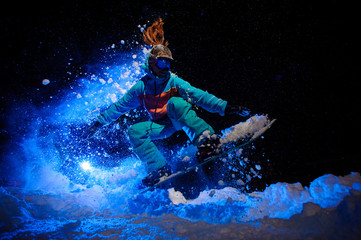 Female snowboarder dressed in a orange and blue sportswear performing tricks on the snow