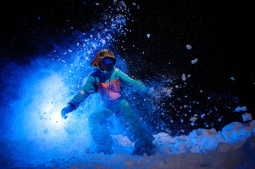 Obraz na płótnie Canvas Active female snowboarder dressed in a orange and blue sportswear making tricks on the snow